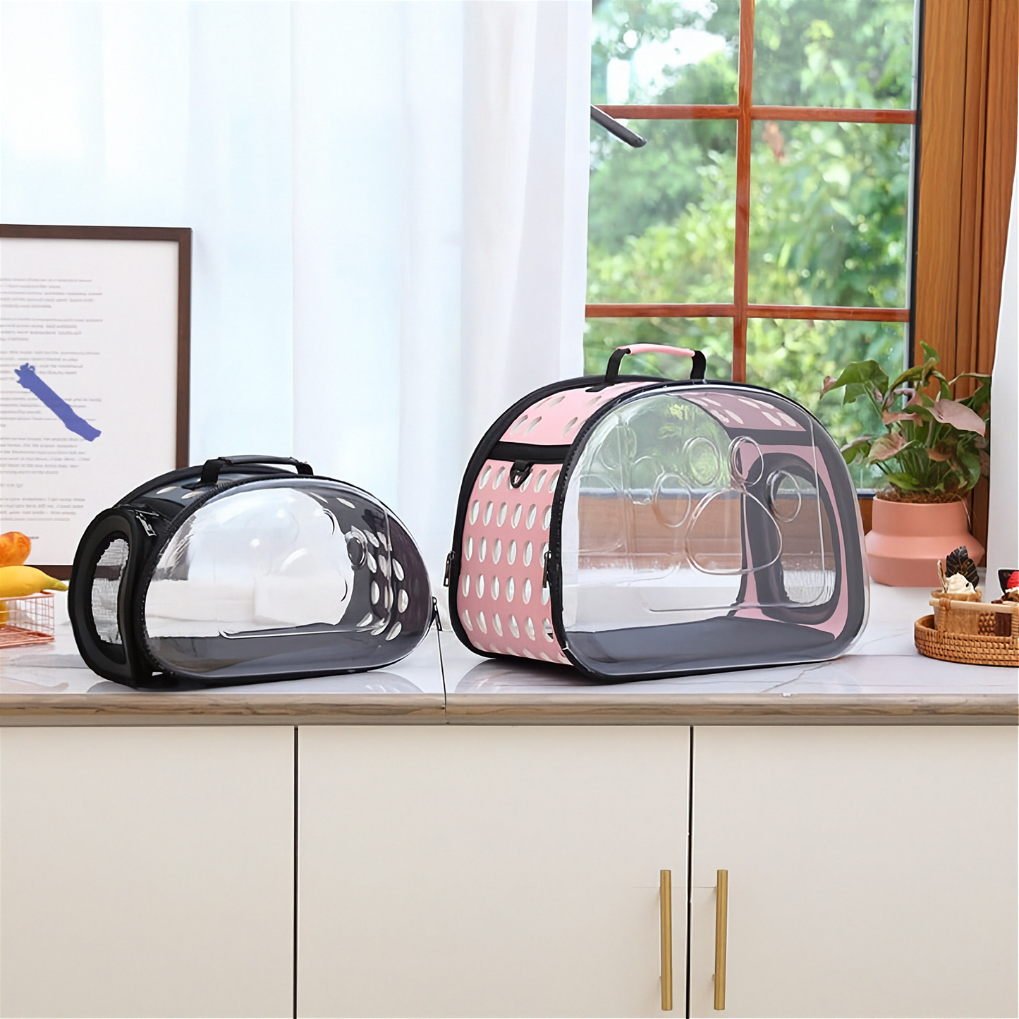 Clear pet carrier with black and pink design on a kitchen counter.