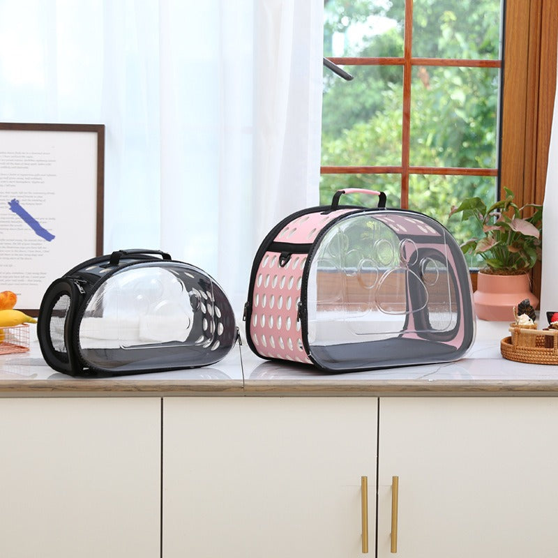 Two pet carriers, one black and one pink with clear sides, on a kitchen counter.